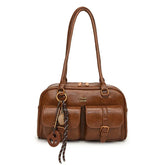 Brown faux leather shoulder bag with dual handles, front pockets, and buckle detail