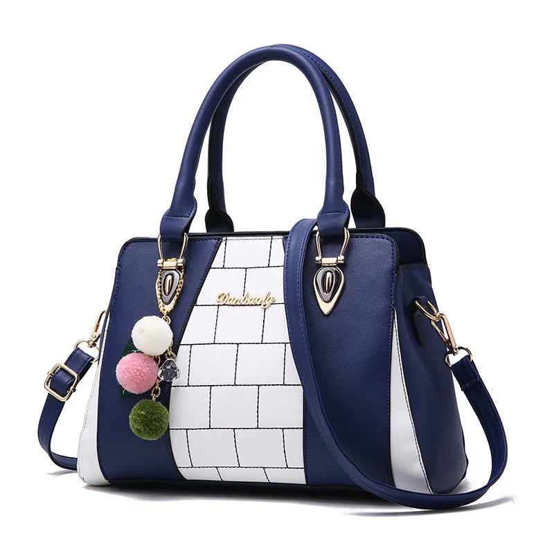 Blue and white structured handbag with faux leather material, geometric panel design, and pom pom charm