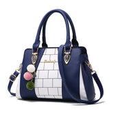 Blue and white structured handbag with faux leather material, geometric panel design, and pom pom charm