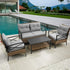 Modern outdoor patio set with gray cushions, rattan frame, and black metal arms by a pool.