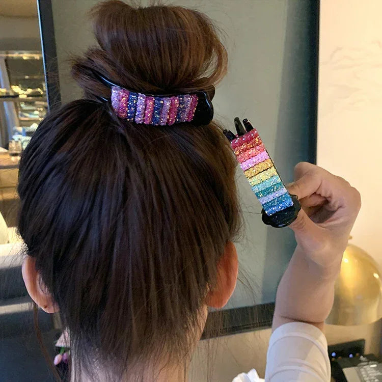 Woman with brown hair in a bun secured by a colorful glitter striped hair claw clip