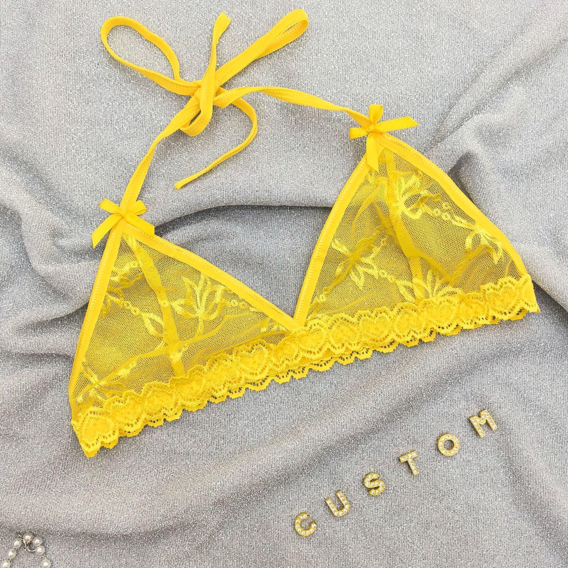 Yellow lace bralette with floral mesh, adjustable tie straps, and scalloped trim on gray fabric