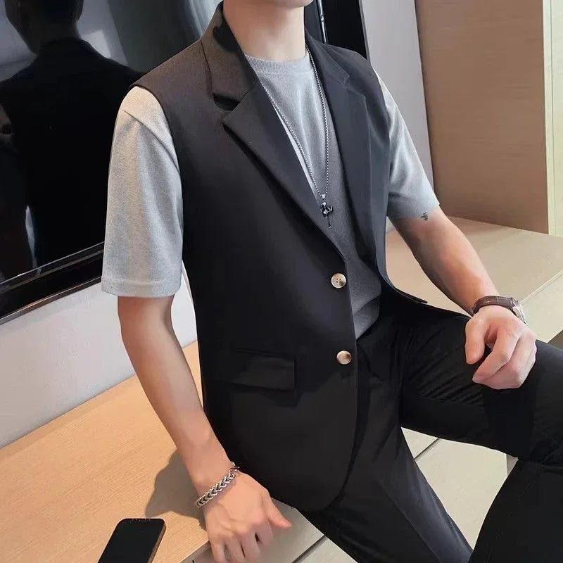 Man wearing a black sleeveless blazer over a gray t-shirt and slim black pants
