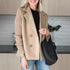 Woman wearing a beige double-breasted wool blend blazer with ribbed sleeves, black top, and light blue jeans.