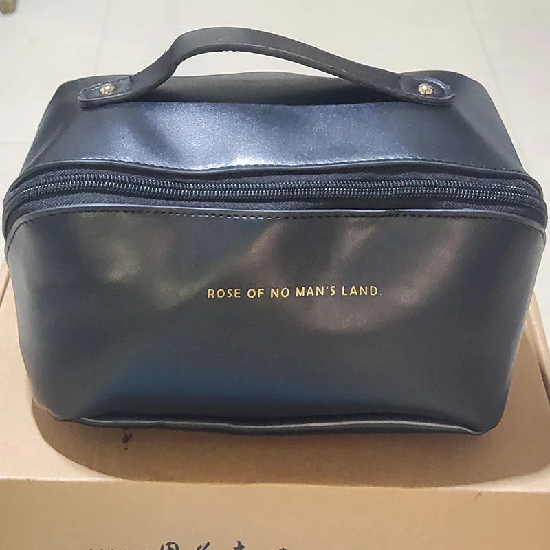 Black faux leather zippered clutch bag with top handle and gold text, rectangular shape