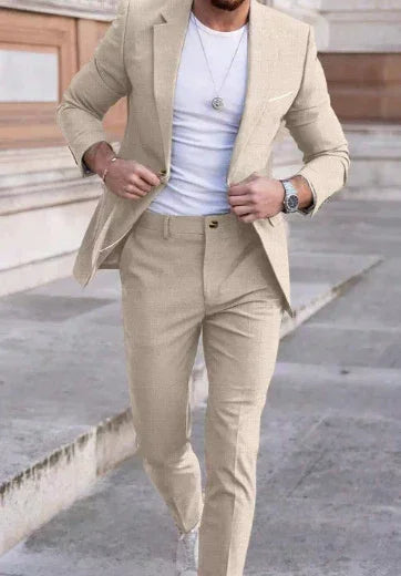 Man wearing slim fit beige suit with white t-shirt, tailored pants, and wristwatch outdoors
