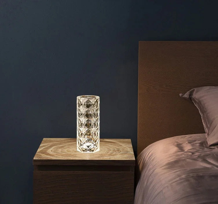 Crystal textured glass lamp on wooden nightstand beside bed with mauve bedding