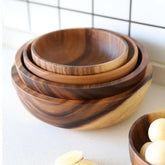 Stacked natural wood serving bowls with smooth finish and warm brown tones on a kitchen counter