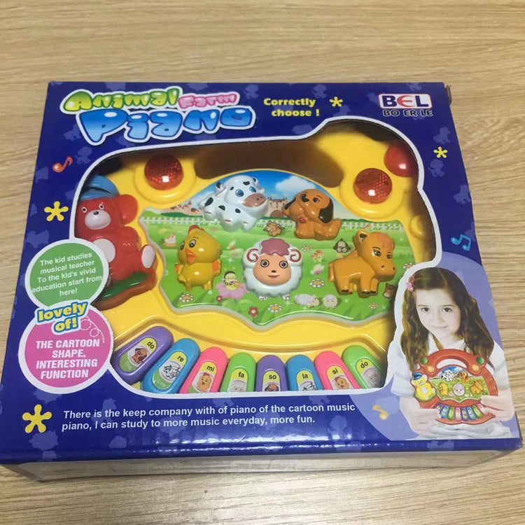 Colorful animal farm-themed toy piano with cartoon animal figures in box on wooden table.