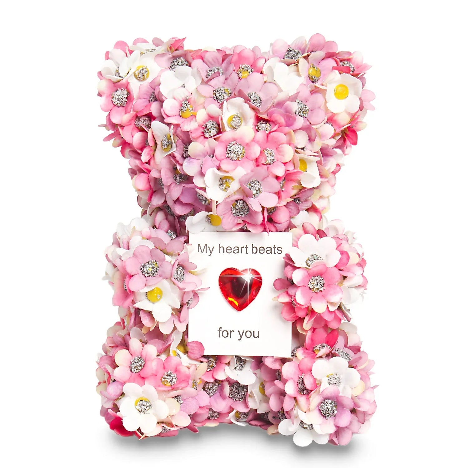 Decorative teddy bear covered in pink and white artificial flowers, holding a heart-shaped card.