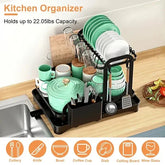 Double-tier black dish drying rack with mint green ceramic dishes, cups, and utensils on countertop
