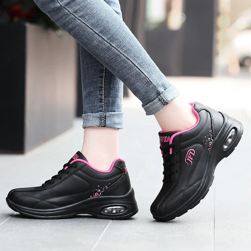 Black athletic sneakers with pink accents and air-cushioned soles, paired with skinny jeans.