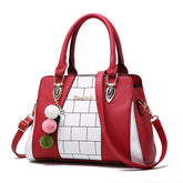 Red and white faux leather handbag with geometric pattern and pom pom charms, medium structured fit