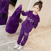 Girl in purple plush velvet tracksuit set with relaxed fit, holding matching hooded jacket.