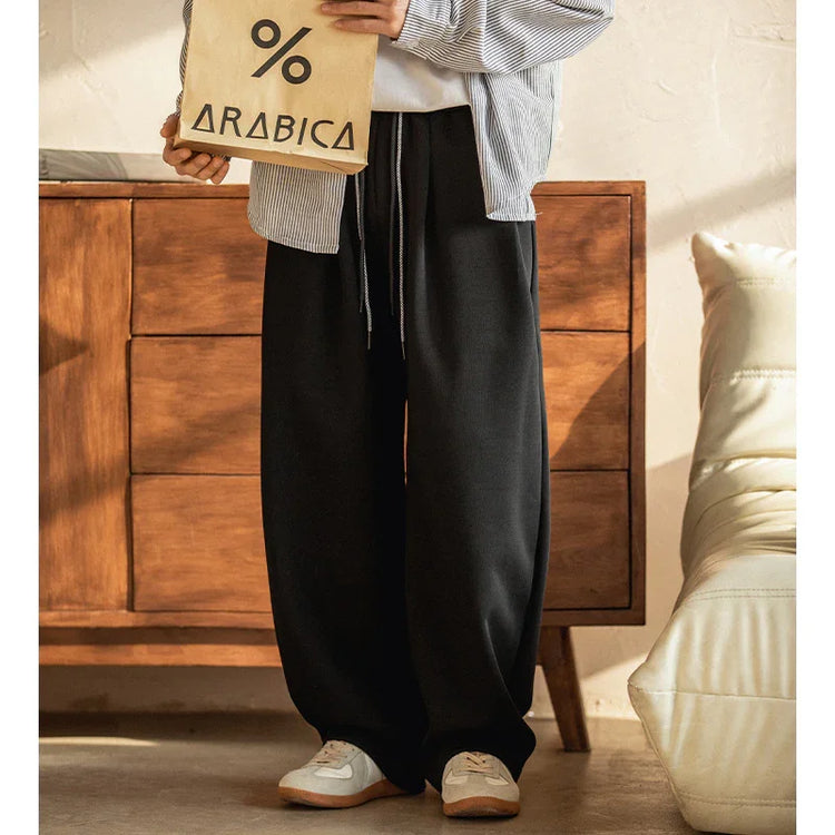 Wide-leg black streetwear pants with relaxed fit, drawstring waist, and casual sneakers