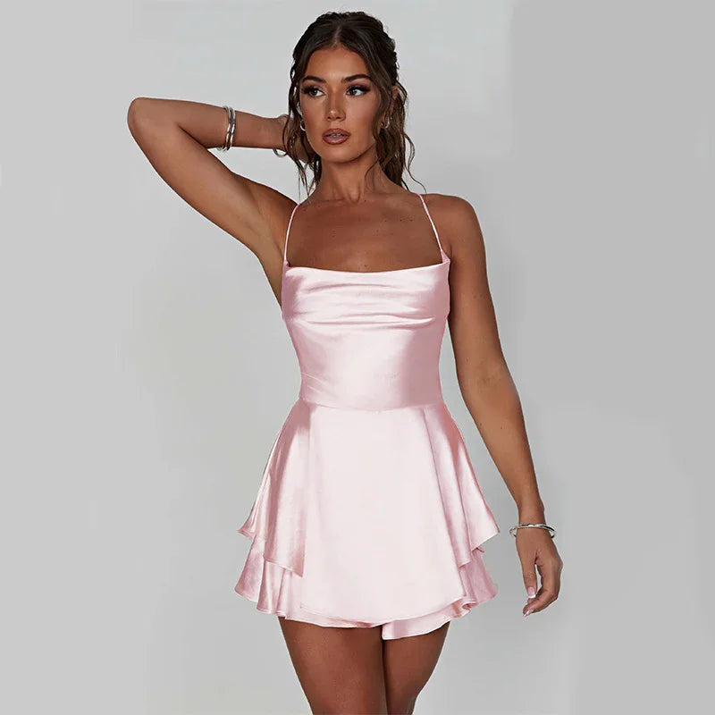 Woman wearing a light pink satin mini dress with spaghetti straps and layered skirt