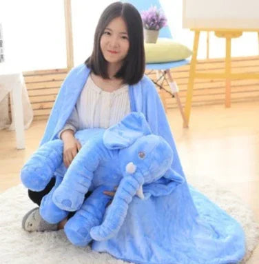 Woman in cozy white long-sleeve top and soft blue fleece cape, holding large blue plush elephant.