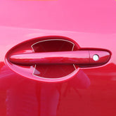 Close-up of a shiny red car door handle with smooth, glossy paint finish