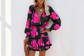 Woman wearing a black long-sleeve mini dress with vibrant pink floral print and ruffled hem.