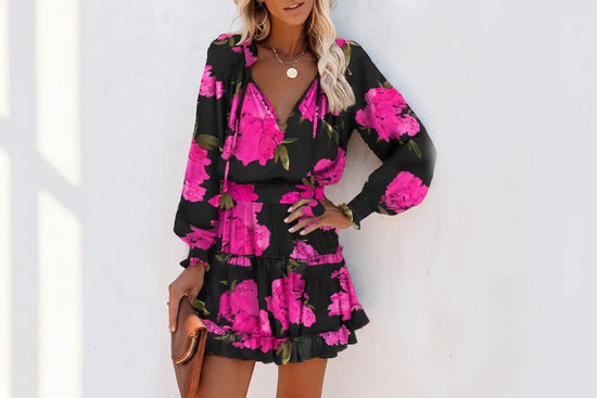 Woman wearing a black long-sleeve mini dress with vibrant pink floral print and ruffled hem.