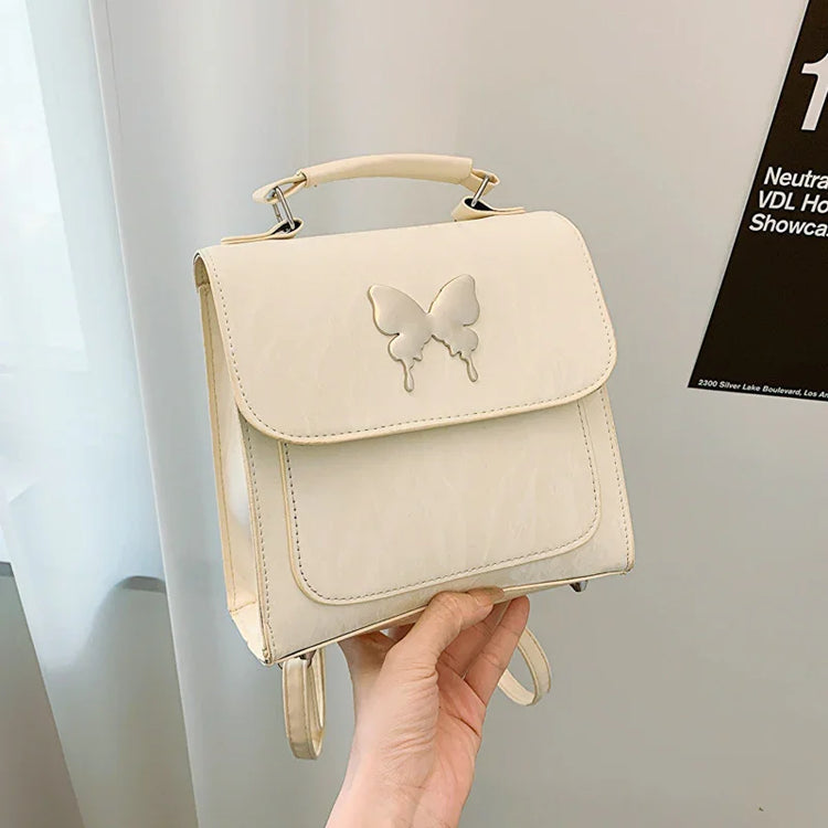 Cream faux leather mini backpack with butterfly detail, modern square shape, top handle
