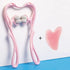 Pink handheld massage roller and heart-shaped gua sha tool on blue background