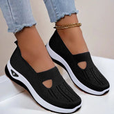 Black mesh slip-on sneakers with white sole, breathable knit material, casual fit, worn with jeans.