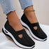 Black mesh slip-on sneakers with white sole, breathable knit material, casual fit, worn with jeans.