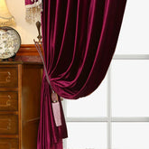 Plush burgundy velvet curtain with decorative tassel, draped in a classic interior setting