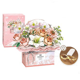 Pink and white artificial flower bouquet in gift box with LED light, includes roses and daisies.