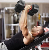 Man in black sleeveless athletic tank top using adjustable dumbbells on gym bench
