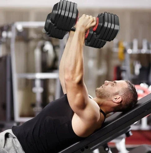 Man in black sleeveless athletic tank top using adjustable dumbbells on gym bench