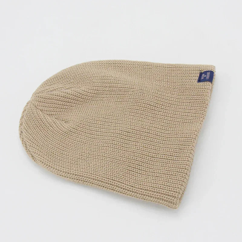 Beige knitted beanie hat with relaxed fit, soft textured material, minimalist style
