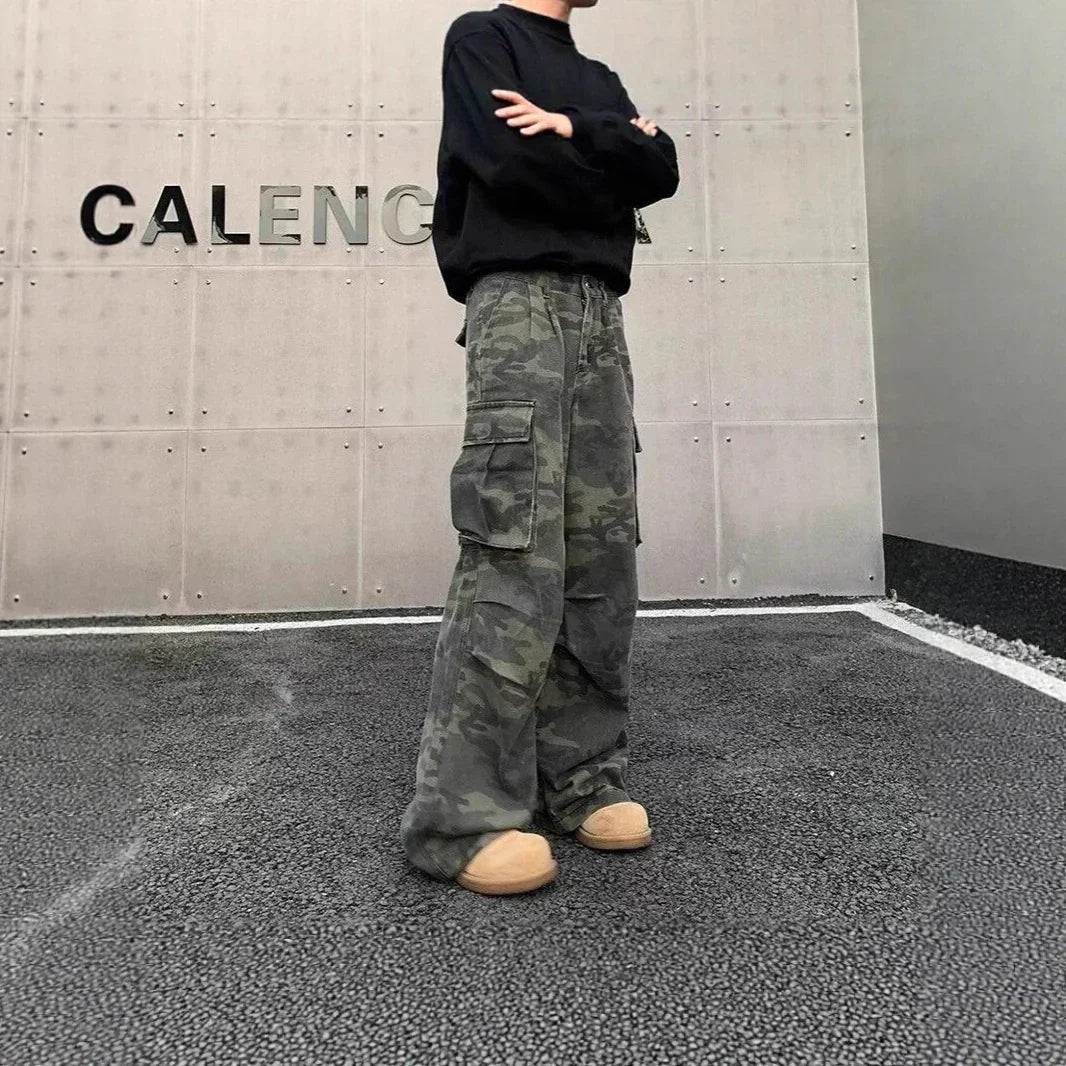 Man wearing baggy camo cargo pants, black sweatshirt, and chunky beige sneakers in urban setting