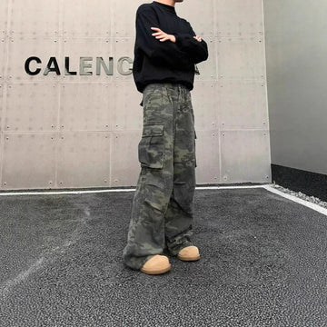 Man wearing baggy camo cargo pants, black sweatshirt, and chunky beige sneakers in urban setting