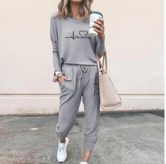 Woman wearing gray casual lounge set with heart graphic, drawstring joggers, and white sneakers
