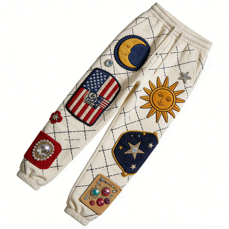 Cream jogger pants with colorful embroidered patches and gem accents, relaxed streetwear fit.