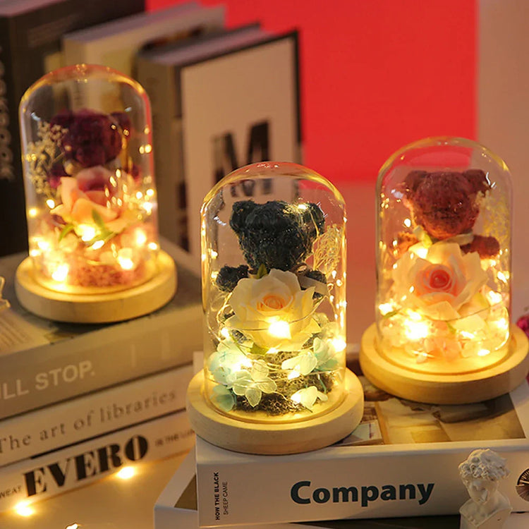 Decorative glass domes with plush bear figurines, artificial flowers, and warm LED lights