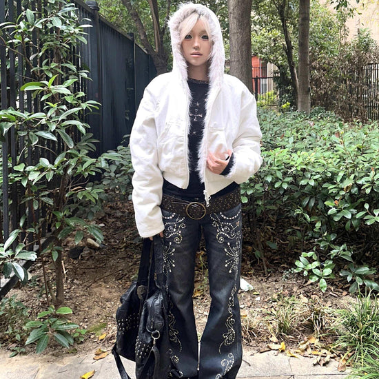 Person wearing a white faux fur hooded jacket and black embellished flared jeans outdoors
