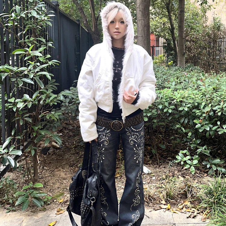 Person wearing a white faux fur hooded jacket and black embellished flared jeans outdoors