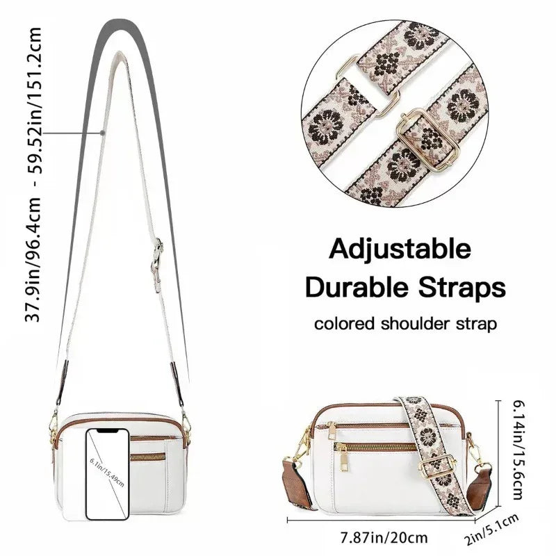 White crossbody bag with adjustable floral shoulder strap, gold zippers, and leather accents