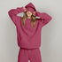 Woman wearing oversized pink hoodie and matching sweatpants, casual streetwear style.