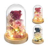 Glass dome with preserved flower bear, LED fairy lights, and roses on wooden base