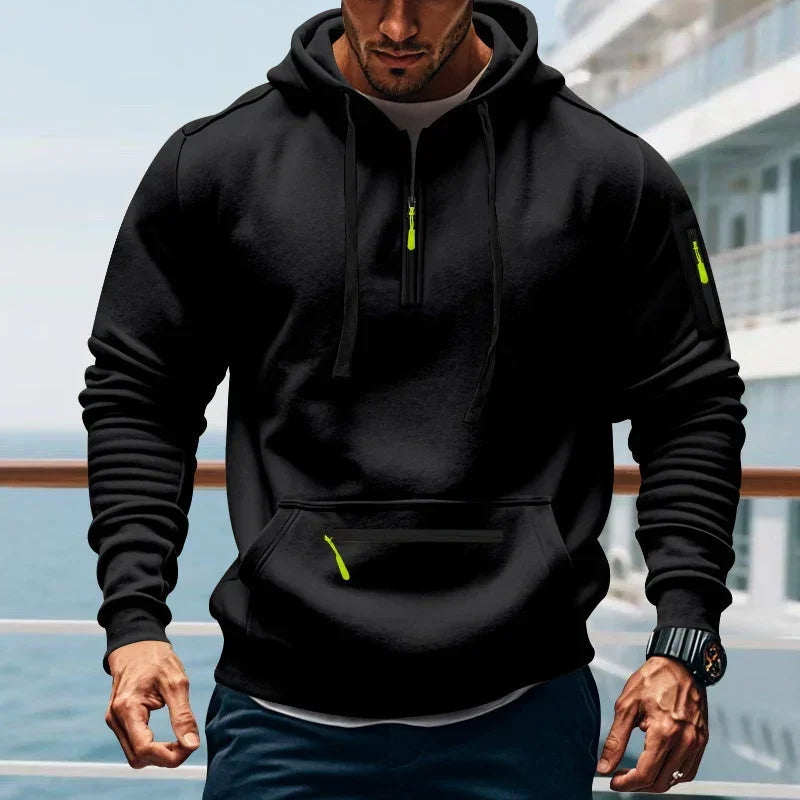 Man wearing a black pullover hoodie with neon green zipper accents, sporty relaxed fit