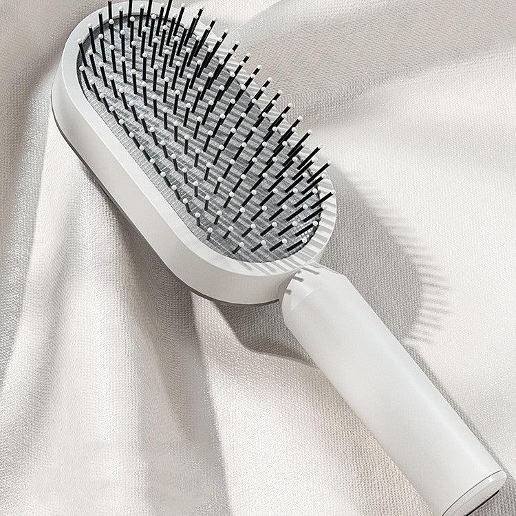Modern white paddle hair brush with black bristles on a soft, textured fabric background