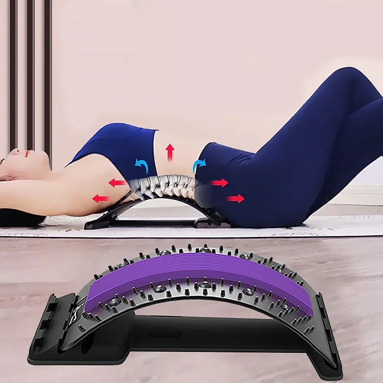 Woman in fitted navy blue activewear using a purple back stretcher on a yoga mat.