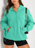 Woman wearing loose teal half-zip hoodie with kangaroo pocket and black shorts, casual streetwear style