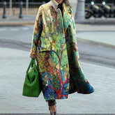 Colorful oversized long coat with nature-inspired print, loose fit, worn with green handbag.