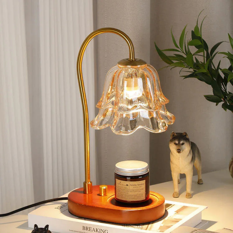 Modern desk with gold and glass flower-shaped lamp, brown candle, and minimal decor.