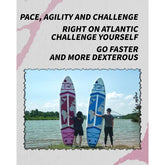 Two people in casual streetwear, standing beside pink and blue paddleboards by a lake
